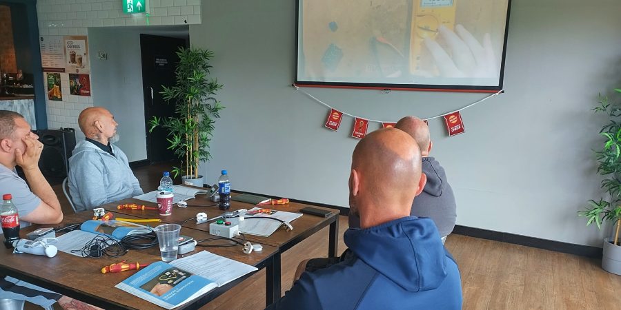 Learners completing practical PAT testing training at Powerleague Liverpool, with test equipment, leads and course materials on the tables.